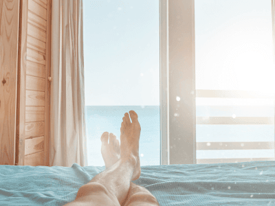 Ein Mensch liegt entspannt auf einem Bett und blickt aufs Meer.